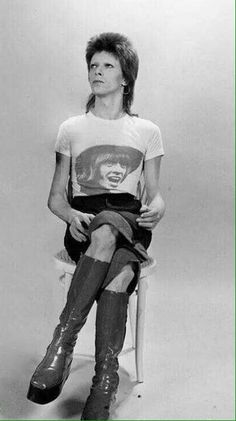 black and white photograph of woman sitting on chair with leg up in front of her