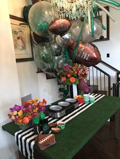 a table with balloons, plates and flowers on it in front of a staircase case