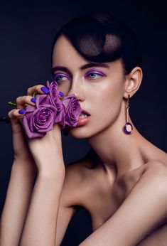 a woman with purple makeup and flowers in her hand