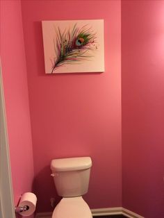 a bathroom with pink walls and a white toilet in the corner next to a painting on the wall