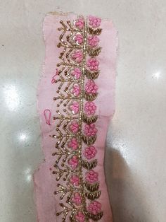 a piece of pink fabric with gold thread and flowers