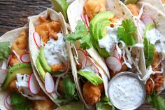 fish tacos with avocado, sour cream sauce and cilantro wedges