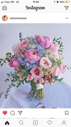 a bouquet of pink and blue flowers sitting on top of a white table next to an instagram