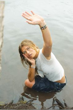 a woman sitting in the water with her hand up