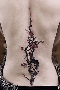 the back of a woman's body with flowers on it and a bird perched on a branch