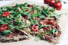 a pizza topped with lots of veggies on top of a wooden cutting board