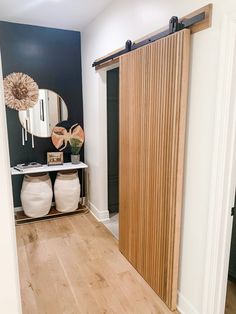 an open door leading to a hallway with wooden floors and white vases on the floor