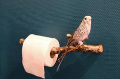 a bird sitting on top of a branch next to a roll of toilet paper