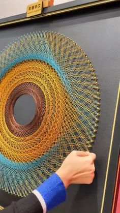 a person is working on a piece of art that looks like a circular object with multiple colors