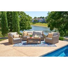 an outdoor living room with couches and tables next to a pool