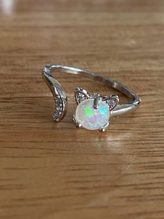 This super cute, silver tone, cat ring is very cute! It's is adjustable and has a small simulate opal in the center and small rhinestones in the tail. It's made of copper. It's a great small accessory to add to any outfit and show your love for your cat! Cute Cat Design Round Jewelry, Cute Cat Design Jewelry, Cute Round Cat Design Jewelry, Silver Cat Ears Jewelry, Silver Cat Design Ring, Silver Cat Design Promise Ring, Cute Silver Ring Jewelry, Cute Silver Open Ring Jewelry, Cute Silver Open Ring