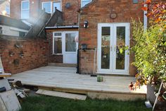 a house with a wooden deck in front of it and stairs leading up to the back door