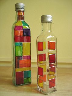 two colorful bottles sitting on top of a wooden floor next to each other with different colored squares in them