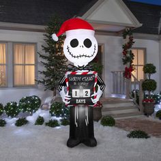 a large inflatable skeleton wearing a santa hat stands in front of a house decorated for christmas