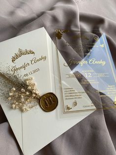 two wedding cards and a wax seal on a bed