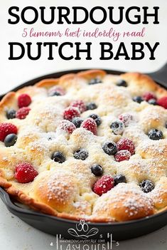 a close up of a pie with berries and powdered sugar on top in a pan