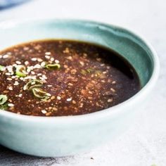 a blue bowl filled with soup sitting on top of a table next to a spoon