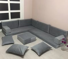 a living room with grey couches and pillows on the floor