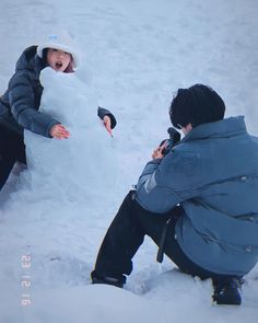 two children building a snowman in the snow with one child holding his hand out