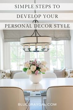 a white dining room table with chairs and flowers in the center on top of it