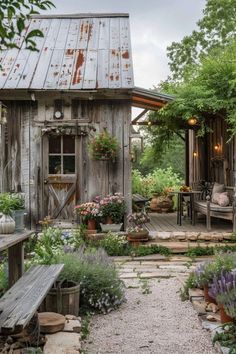 an old wooden shed is surrounded by flowers and greenery