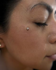 a close up of a woman with a nose piercing on her left ear and eyeliner