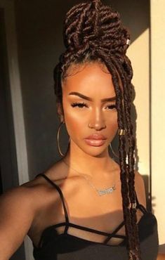 a woman with long braids standing in front of a door wearing a black top