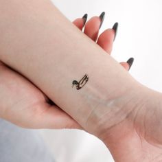 a small tattoo on the wrist of a woman's left arm, which is decorated with two birds