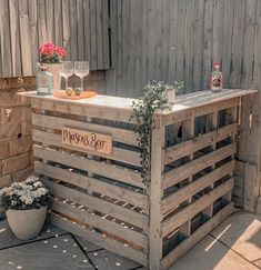 an outdoor bar made out of wooden pallets with flowers and bottles on the counter