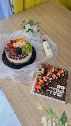 there is a cake on the table with fruit and flowers next to it that says happy birthday