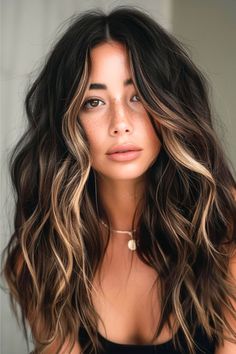 The rich, dark brown base shade of this long hairstyle is textured, and the voluminous cut is enhanced by dazzling hints of gold and caramel, creating a multi-dimensional hue that's sure to turn heads. Click here to see more stunning dark brown hair color ideas. Dark Brown Hair Color, Balayage Brunette