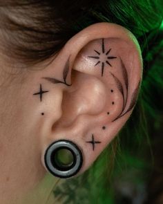 a woman's ear has a star and cross tattoo on it