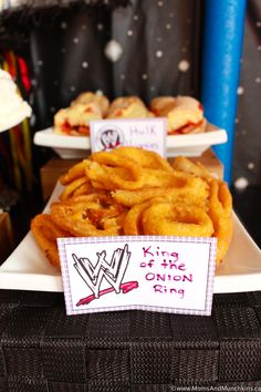 some onion rings are sitting on a white plate with a sign that says king of the onion rings