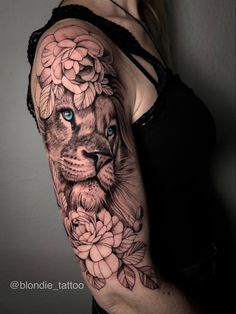 a woman's arm with a lion and flowers tattoo on her left shoulder,