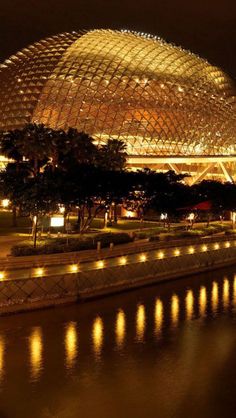 a large building lit up at night next to a body of water with lights on it