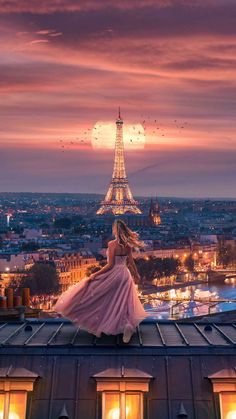 a woman standing on top of a roof in front of the eiffel tower