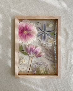 an image of flowers in a frame on a bed sheet with white and pink linens