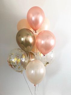 a bunch of balloons with gold and white confetti on them in a vase