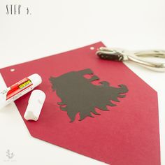 a red piece of paper with a cut out of a lion on it next to some scissors