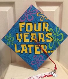 a blue graduation cap with four years later written on it and a tassel hanging from the front