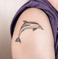 a woman's arm with a dolphin tattoo on the left side of her body