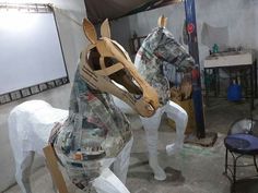 two horses made out of plastic bags in a room filled with other items and tools