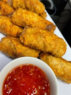 some fried food on a white plate next to a bowl of ketchup and dipping sauce