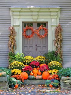 a front porch filled with lots of pumpkins and flowers