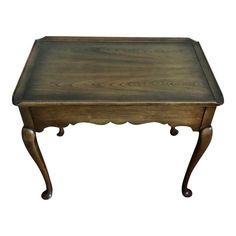 a small wooden table with an ornate design on the top and bottom, sitting against a white background