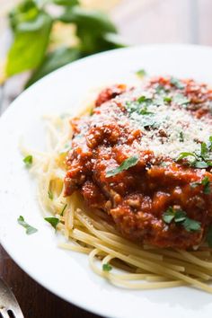 a plate of spaghetti with sauce and parmesan cheese on top, ready to be eaten