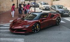 a red sports car is parked on the side of the road as people walk by