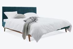 a bed with white sheets and blue headboard