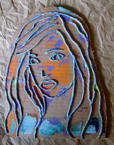 a cardboard cut out of a woman's face with blue and orange paint on it