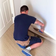 a man sitting on the ground working on a wall